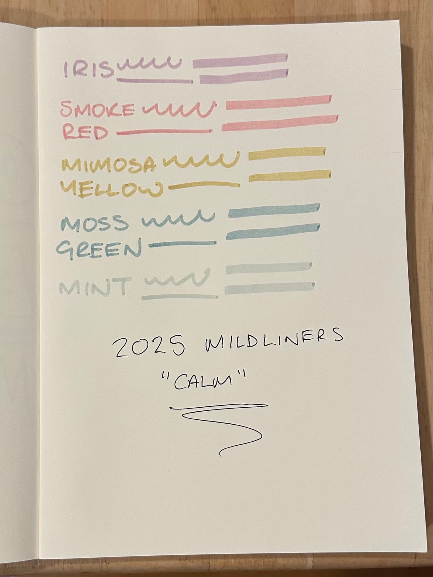 A white notebook with samples of five different color highlighters on it