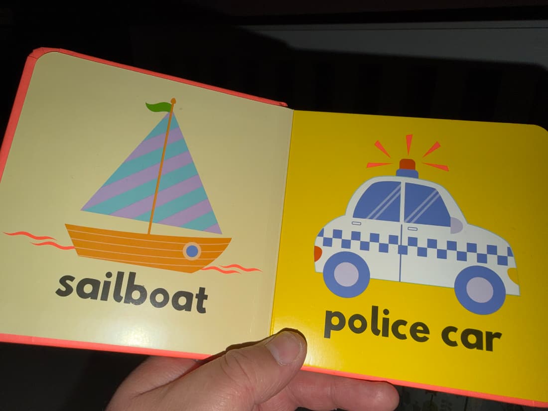 a kids book with a sailboat on the left and police car on the right
