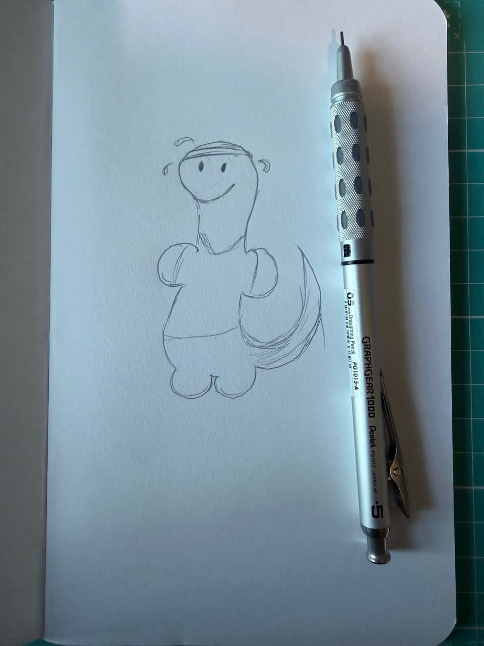 A drawing of a sweating dinosaur on a white notebook with a metal pencil next to it.