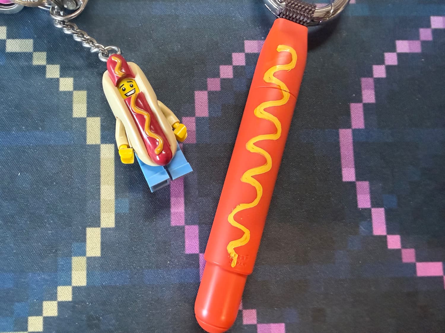 A Lego hot dog man next to an orange pen with mustard painted on