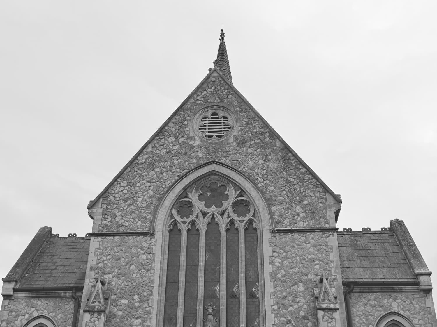 A black and white photo of the top of a church with a white sky behind it