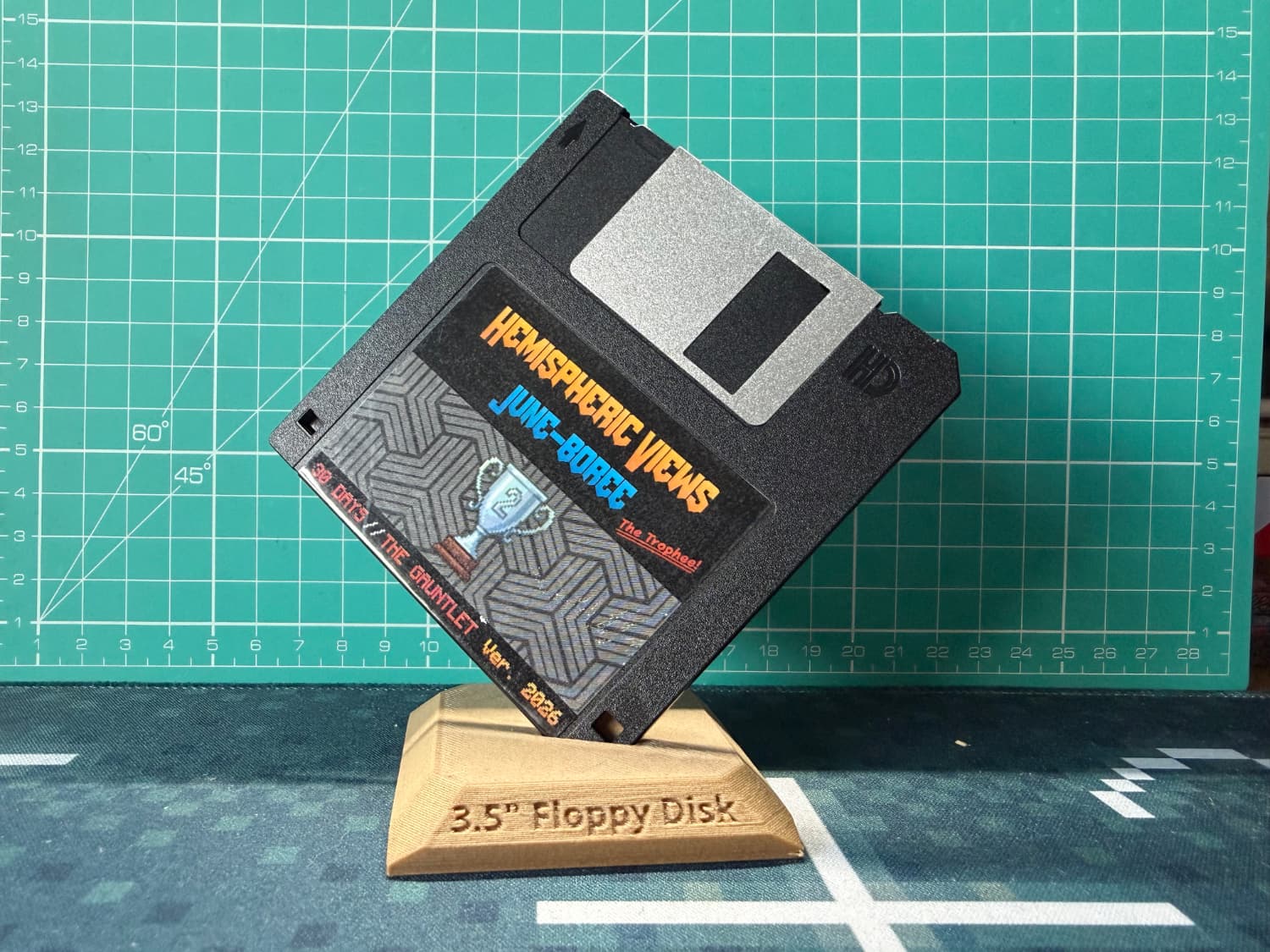 A floppy disc on a 3d=-printed stand on a desk. The label says Hemispheric Views June-Boree and it has a second place trophy on it