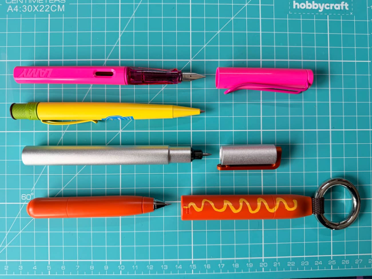 Four pens of different sizes on a cutting board showing the size different between the Pen N and the other pens