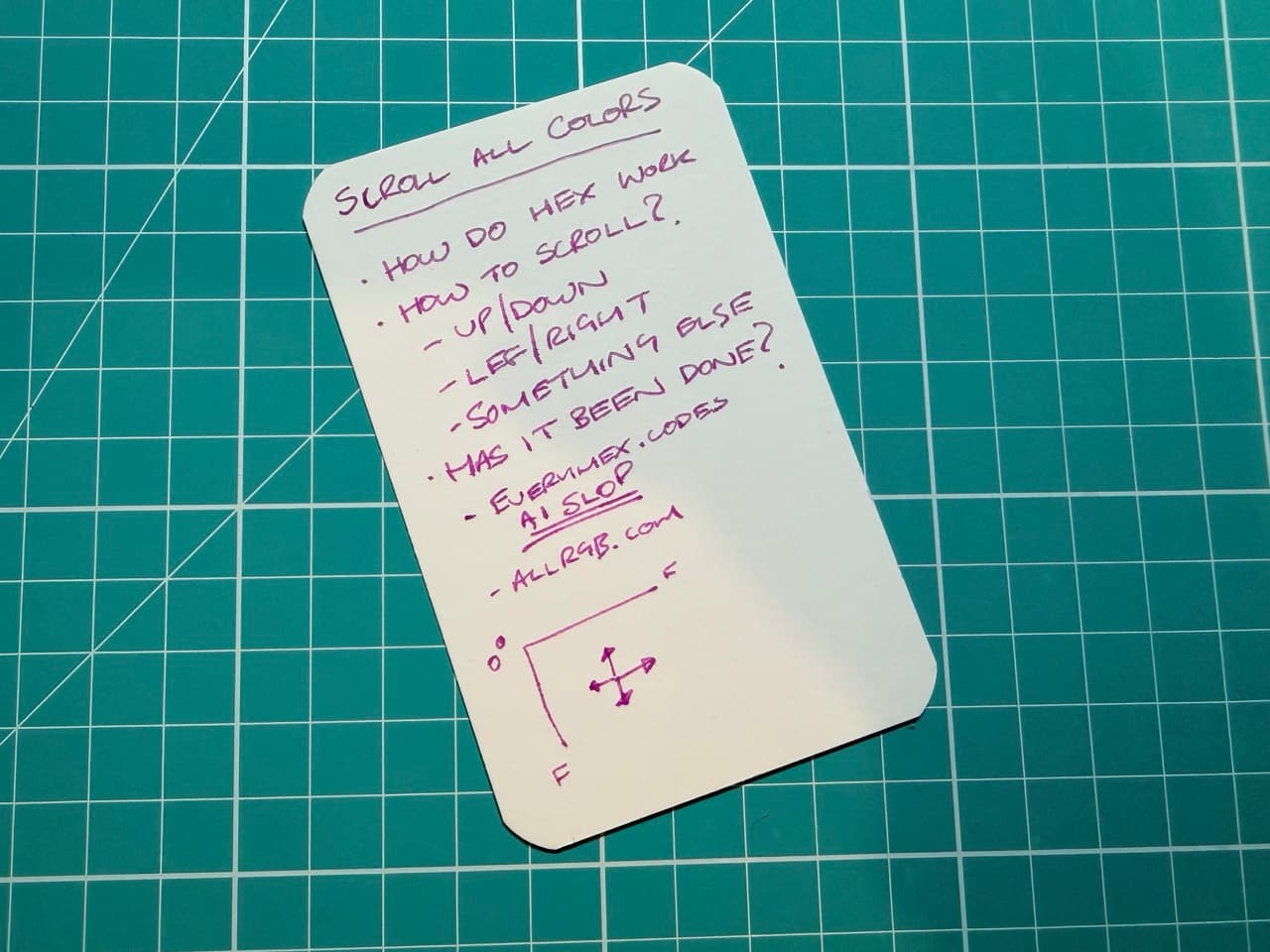 An index card on a green cutting board. The card says "Scroll All Colors" at the top then some bullet points about how to implement such a thing