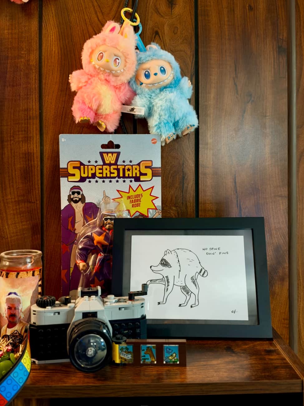 A photo of some collectables and a framed drawing of Jimothy the raccoon.