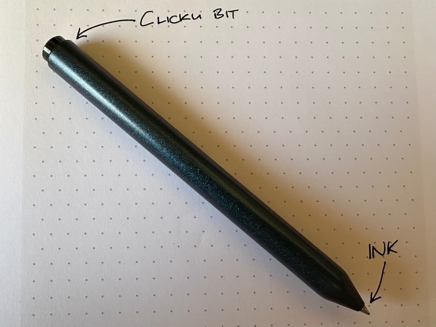 The Mark One pen on dotgrid paper with arrows showing where the clicky bit is and where the ink comes out
